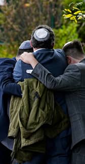 Members of the Jewish community comfort each other near to the Heaton Park Hebrew Congregation synagogue in Crumpsall, Manchester
