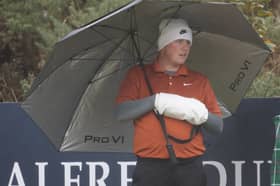 Wearing a muff to keep his hands warm, Bob MacIntyre shelters from the rain in the second round of the Alfred Dunhill Links Championship at Kingsbarns