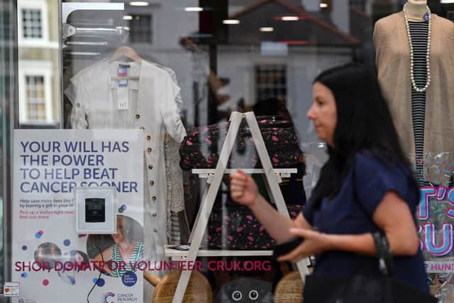 A woman walks past a Cancer Research UK store in London. The charity shop chain will close 88 high street shops by May 2026, with 100 more expected by April 2027 (Photo: BEN STANSALL/AFP via Getty Images)