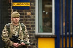 A soldier stands in the rain outside a military barracks.