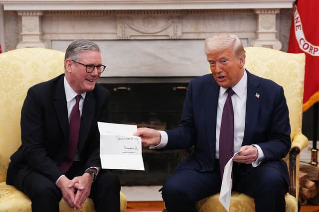 US President Donald Trump is presented with a letter from King Charles, who invited him for an unprecedented second state visit, during his meeting with Prime Minister Sir Keir Starmer in the Oval Office at the White House in Washington DC