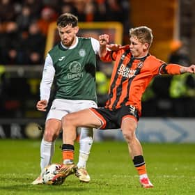 Dundee United's Zac Sapsford, wearing a black armband, challenges Hibs defender Jack Iredale. 