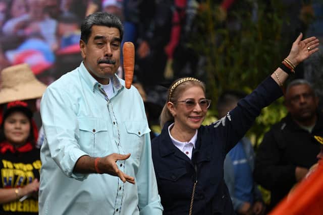 TOPSHOT - Venezuela's President Nicolas Maduro tosses a carrot into the air upon his arrival with First Lady Cilia Flores at a rally marking the anniversary of the Battle of Santa Ines, in Caracas on December 10, 2025. (Photo by Federico PARRA / AFP via Getty Images)