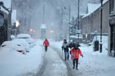 Huntly residents walk in the roads during snowfall on Monday