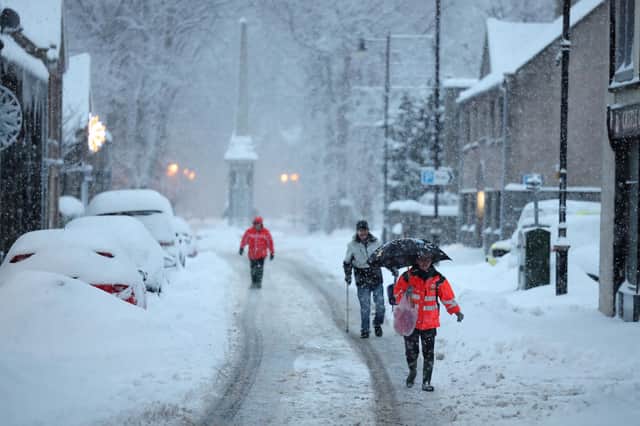 Huntly residents walk in the roads during snowfall on Monday