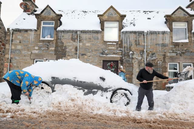 People clear cars after heavy snowfall in Dufftown, Moray, on Monday