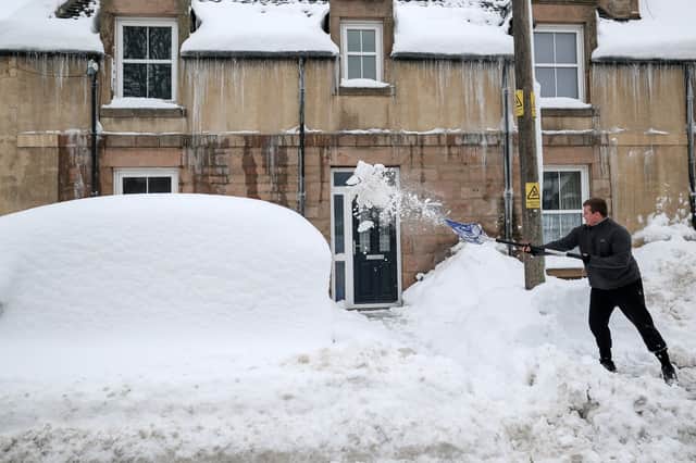 A man clears snow from outside his home in Lumsden, Aberdeenshire, on Tuesday
