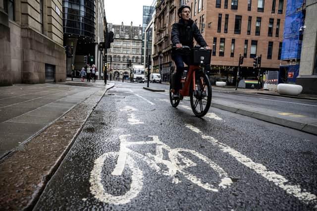 Alastair Dalton riding a Voi bike on a segregated cycle lane on Waterloo Street in Glasgow city centre