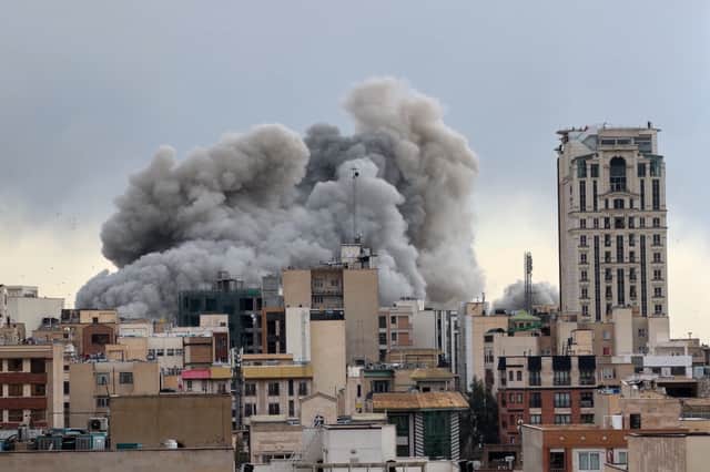 A plume of smoke rises after a strike in Tehran on Monday