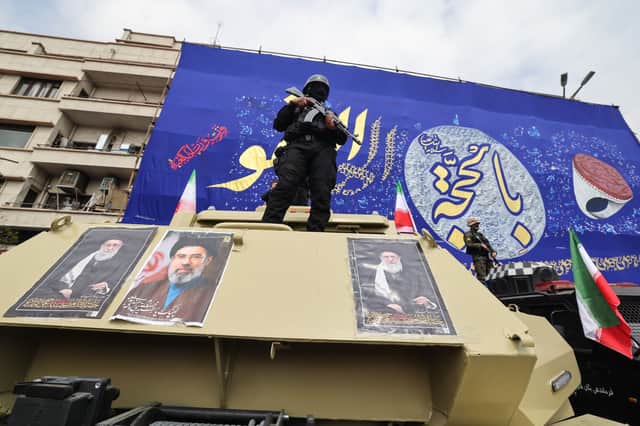 Members of the security forces stand guard on armoured vehicles plastered with portraits of Iran's slain supreme leader Ayatollah Ali Khamenei and his son, Iran's new supreme leader Ayatollah Mojtaba Khamenei, during the funerals of Iran's Revolutionary Guards Corps commanders, army commanders and others killed in US and Israeli strikes on Iran
