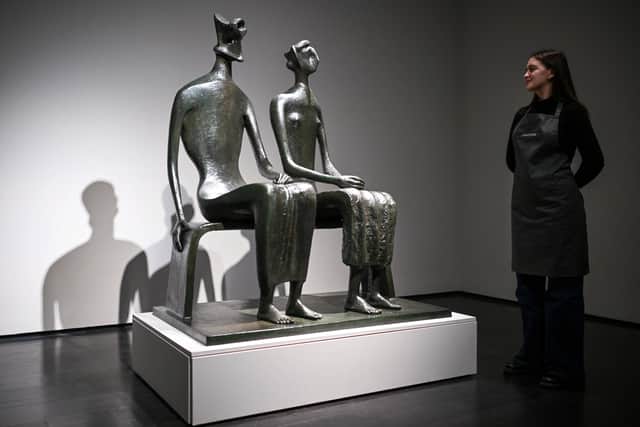 A gallery assistant poses with artist Henry Moore's masterpiece 'King and Queen'.