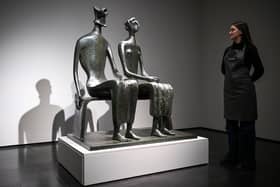 A gallery assistant poses with artist Henry Moore's masterpiece 'King and Queen'.