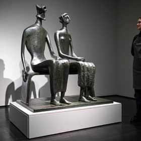 A gallery assistant poses with artist Henry Moore's masterpiece 'King and Queen'.