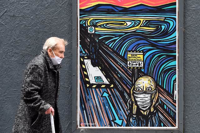 A pedestrian walks past graffiti in Glasgow in September 2020. It depicts the figure in Edvard Munch's famous painting, The Scream, wearing a face mask (Picture: Andy Buchanan)