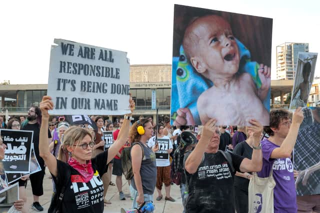 Israeli activists hold up pictures of starving Palestinian children in Gaza at a protest in Tel Aviv in July last year (Picture: Jack Guez)