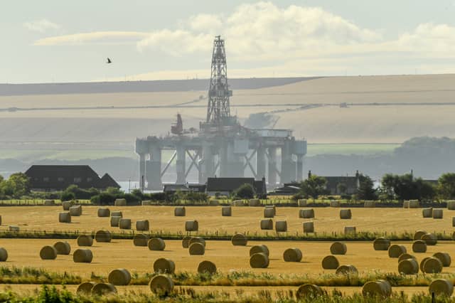 An oil rig in the Cromarty Firth is seen towering over a field of hay bales near Invergordon