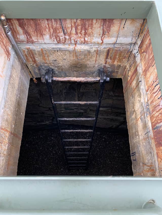 Beneath the trapdoor is the ladder descending into the tomb.