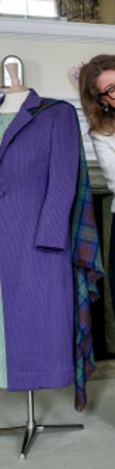 A member of staff from the Royal Trust Collection alongside a green day dress, purple coat and purple trilby hat worn by Queen Elizabeth II for the official opening of the Scottish Parliament in July 1999 and a fine candy pink wool crepe dress with white thick boucle tweed wool coat worn at the Garden Party in 2017.
