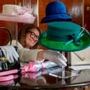A member of staff from the Royal Trust Collection takes a closer look at a green teal wool hat with in-laid straw emerald green brim, designed by Rachel Trevor-Morgan, that the late Queen Elizabeth II wore for the opening of the 6th session of the Scottish Parliament in October 2021 which is on display at the Palace of Holyroodhouse in Edinburgh, the official residence of the monarch in Scotland.