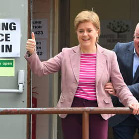 Scotland's First Minister and Scottish National Party leader Nicola Sturgeon reacts as she is surprised by her husband and current chief executive officer of the Scottish National Party Peter Murrell, after casting their vote in local elections, at a polling station, in Glasgow, on May 5, 2022. 