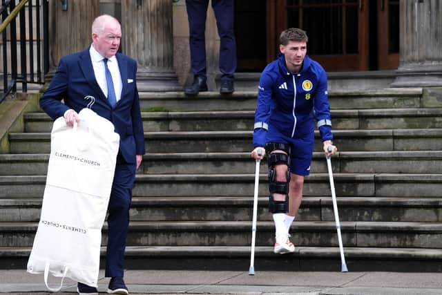 Scotland's Billy Gilmour (right) leaves the team hotel on crutches after the players boarded the bus for Glasgow Airport.