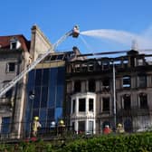 Firefighters work on a building which shows signs of extensive fire damage