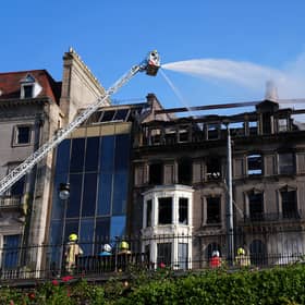 Firefighters work on a building which shows signs of extensive fire damage