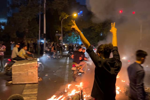A demonstrator makes V-for-victory signs during protests in Iran over the killing of Mahsa Amini in 'morality police' custody in 2022. The regime's response was typically brutal