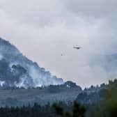 A helicopter carrying water tackles the wildfire burning near Nethy Bridge in Cairngorms National Park in north-east Scotland (Jane Barlow/PA)