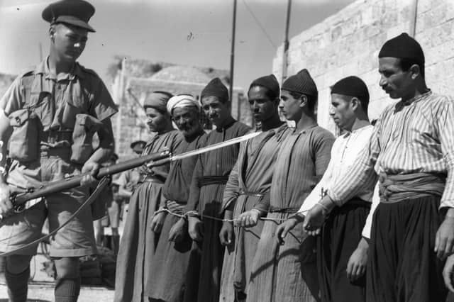 A soldier guards Arab prisoners in the Old City of Jerusalem in 1938, during the British mandate in Palestine (Picture: Fox Photos)
