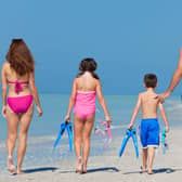 A happy family of mother, father and child, a daughter, walking in swimming costumes on a sunny beach