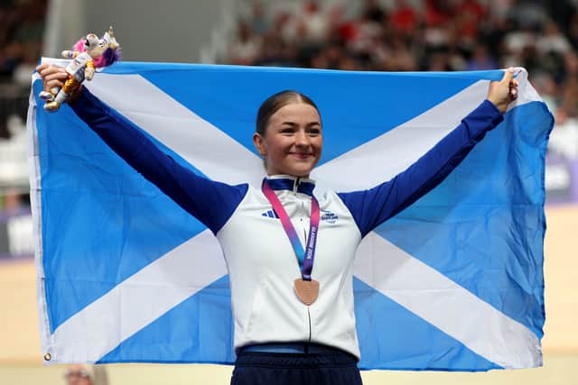 Bronze medalist Erin Boothman of Team Scotland poses with her flag on the podium during the Women's 4000M Individual Pursuit