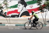 A man cycles past a mural depicting late Iranian supreme leader Ayatollah Ali Khamenei in Tehran as the countries war with the US continues