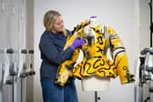 Curator Lisa Mason examines a yellow jacked designed by Jean Muir