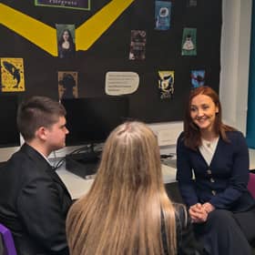 Mairi McAllan smiling while chatting to two pupils in a classroom