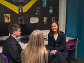 Mairi McAllan smiling while chatting to two pupils in a classroom