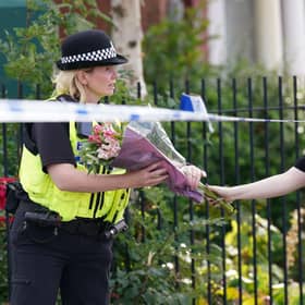 A woman arrives to leave flowers at the scene of a house fire on August 26 in Middlesbrough