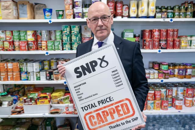 John Swinney in a shop, holding up a sign advertising the SNP's food price cap proposal