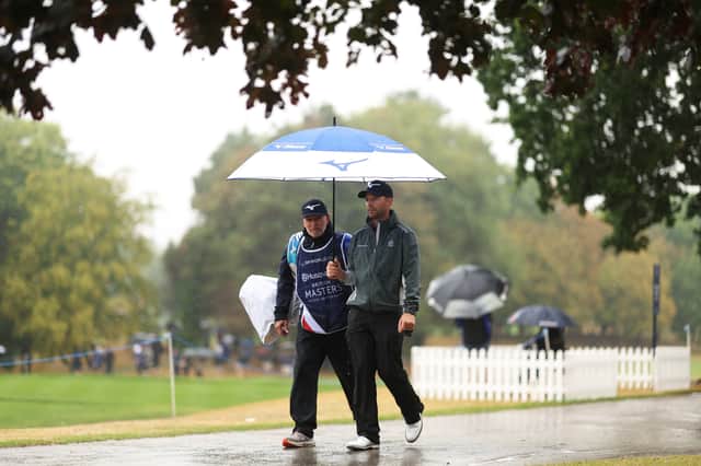 Marcel Schneider of Germany walks with his caddie back to the clubhouse following one of the weather suspensions due to inclement weather at The Belfry