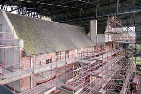 The exposed stone and brick under the roughcast with scaffolding around the house