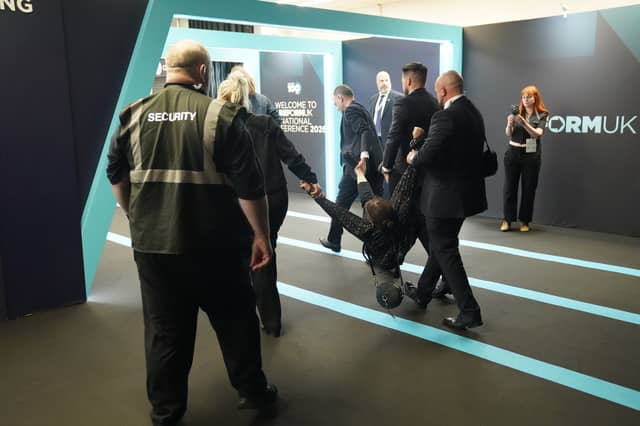 A protester is removed from the Reform UK conference, with footage showing one woman being assaulted by audience members after interrupting Nigel Farage's speech on Friday.
