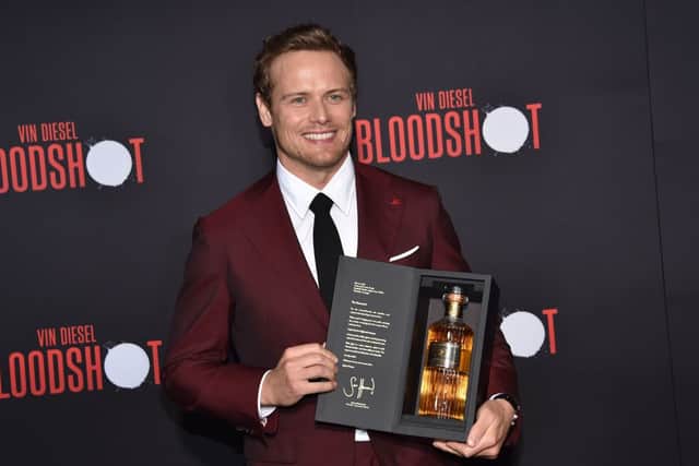 Scottish actor Sam Heughan poses with his newly launched whiskey brand "The Sassenach" as he arrives for the premiere of Sony's "Bloodshot" at the Regency Village theatre on March 10, 2020 in Westwood, California. (Photo by Chris DELMAS / AFP) (Photo by CHRIS DELMAS/AFP via Getty Images)