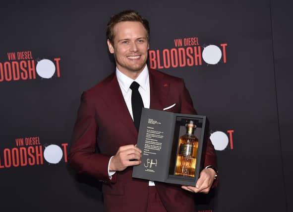 Scottish actor Sam Heughan poses with his newly launched whiskey brand "The Sassenach" as he arrives for the premiere of Sony's "Bloodshot" at the Regency Village theatre on March 10, 2020 in Westwood, California. (Photo by Chris DELMAS / AFP) (Photo by CHRIS DELMAS/AFP via Getty Images)