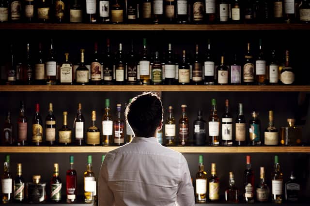 Man looking at many bottles of whisky