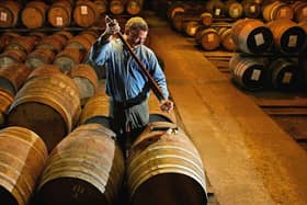 A worker at Bruichladdich distillery takes a whisky sample from a single cask. Picture: Getty