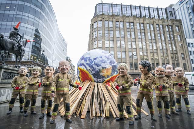 Campaigners wearing 'big heads' of world leaders, including Boris Johnson, Joe Biden, Justin Trudeau and Narendra Modi protest in front of a 10 foot globe with a simulated bonfire the Cop26 summit in Glasgow in 2021