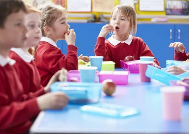 Schoolchildren sitting at table eating lunch