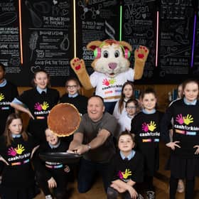 Owner Paul Reynolds flips a pancake with the pupils from St Roch's Primary School and Courage The Cat from CHAS. Photograph: Martin Shields
