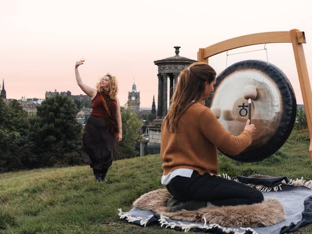 Madeleine Schmoll of The Scotch Malt Whisky Society raising a toast to the start of whisky season on Calton Hill, Edinburgh, with Jo McCoy of Blissness, a gong sound bath practitioner