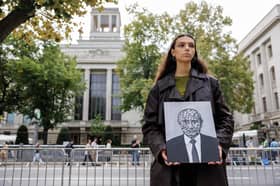 A protester holds a painting of Russian despot Vladimir Putin, showing his head made up of many skulls, during an election-day demonstration outside the Russian Embassy in Berlin, Germany (Picture: Jens Schlater)